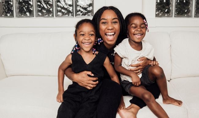 a woman sitting on a couch with two kids