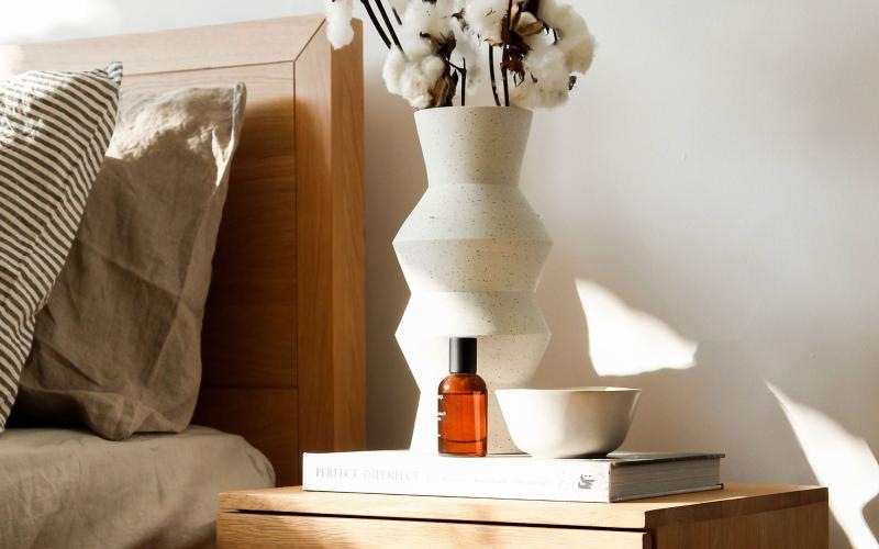 a vase with cotton stems on a bedside table
